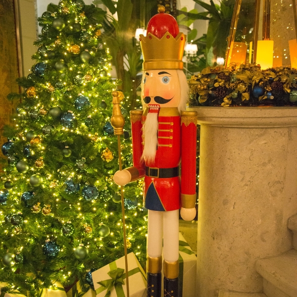 a nutcracker with a gold crown and a gold staff and a christmas tree