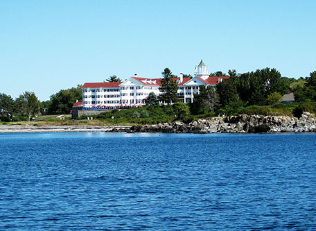 a large white building with red roofs on a hill next to a body of water 24