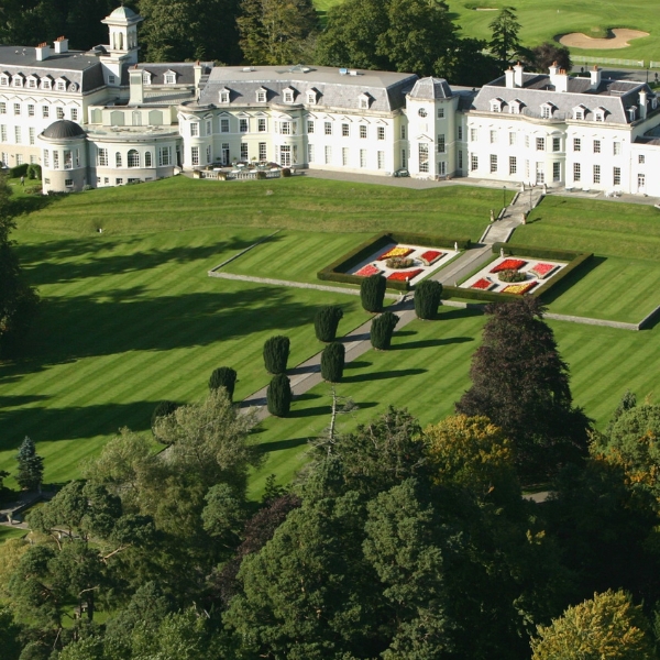 a large white building with a lawn and trees