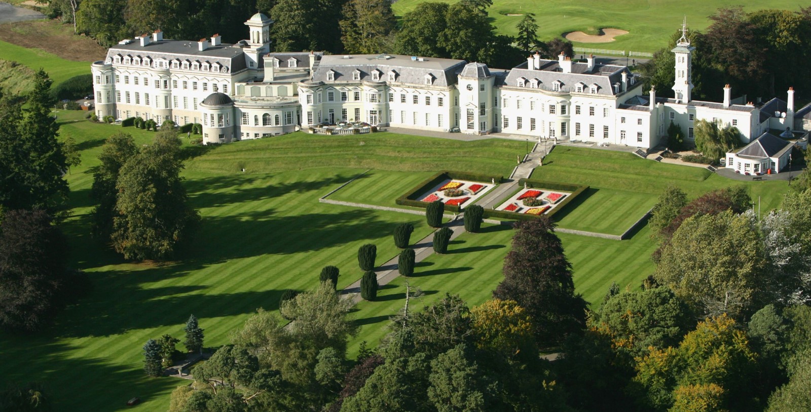 a large white building with a lawn and trees