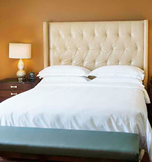 a bed with a white bedding and a lamp