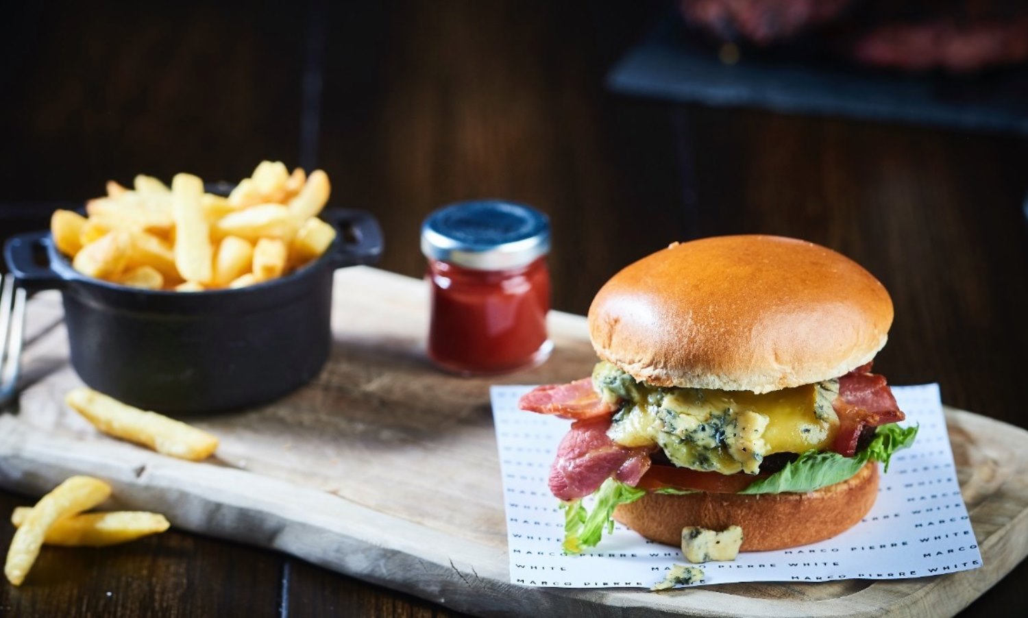 a burger and fries on a wooden board