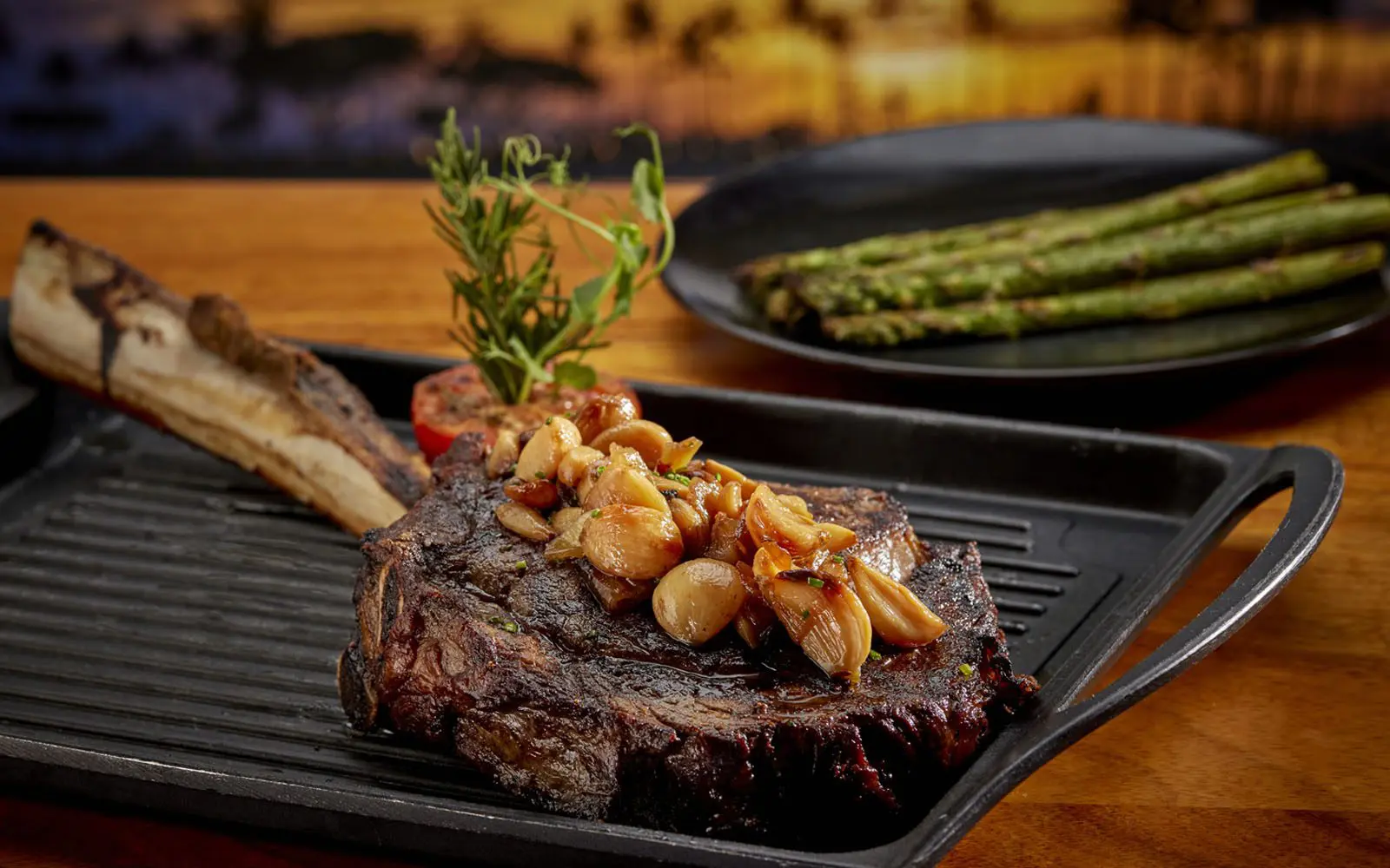 a steak on a grill with asparagus and tomatoes