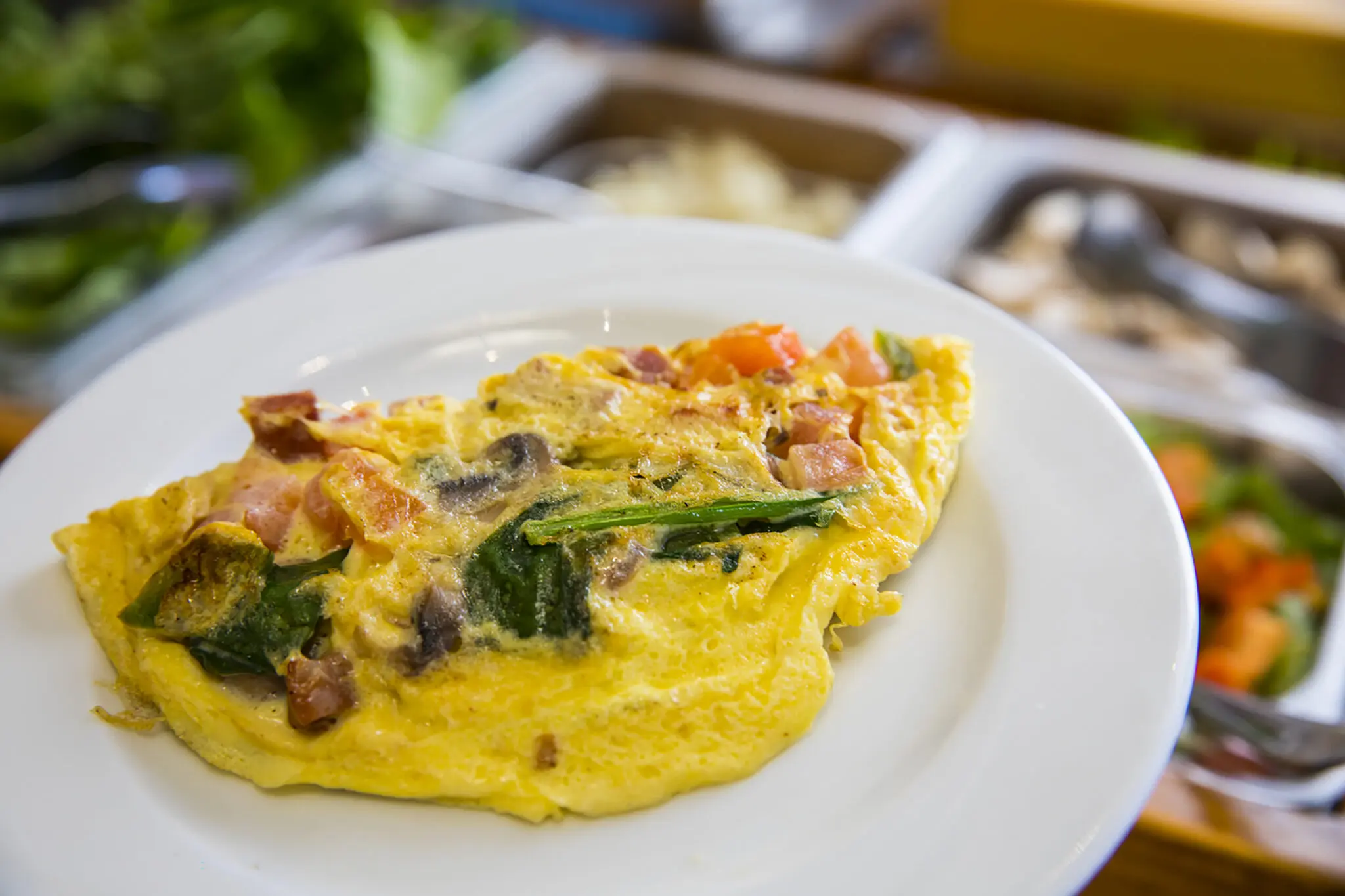a plate of omelette with vegetables and bacon