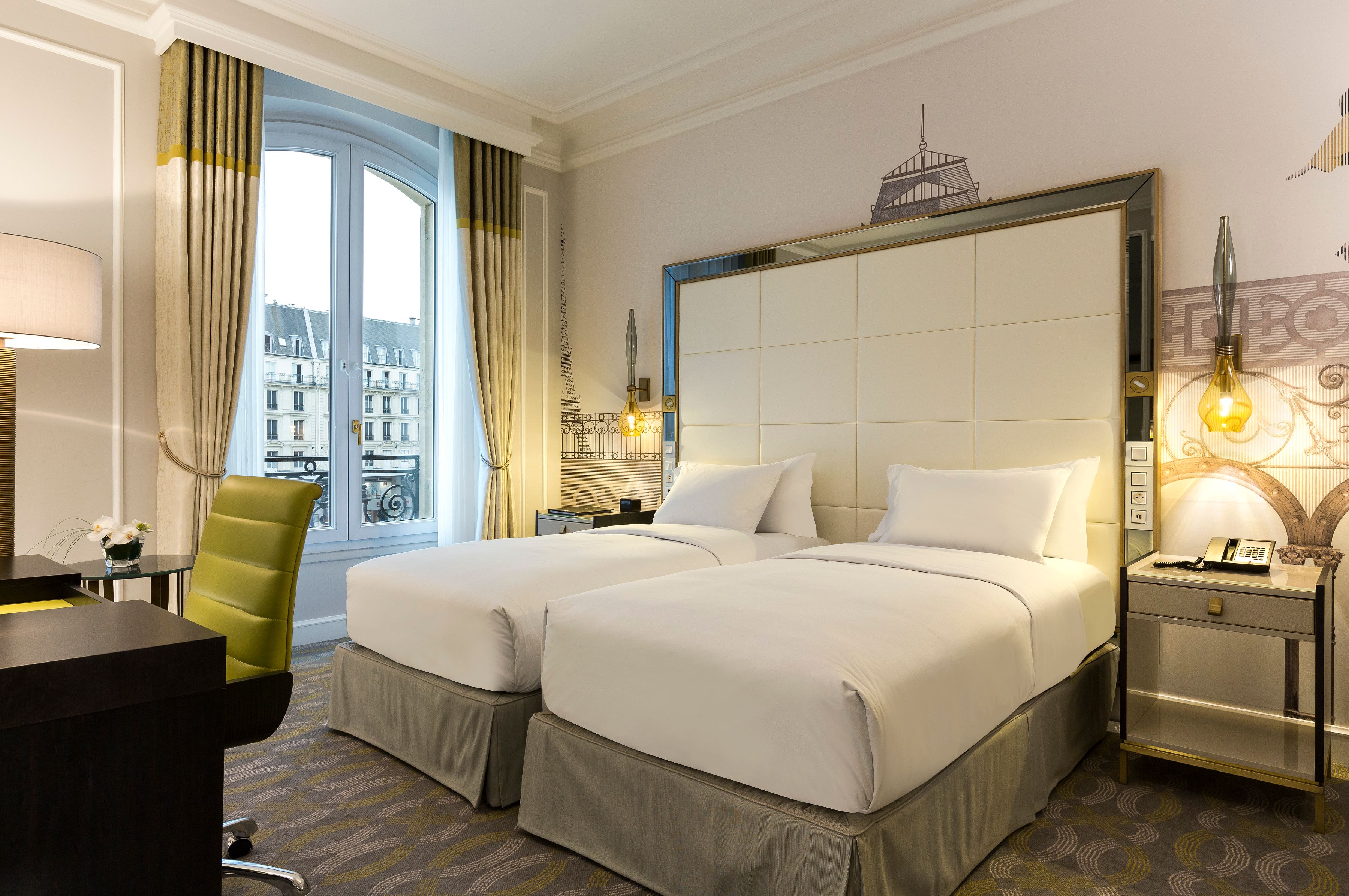 a room with two beds and a green chair