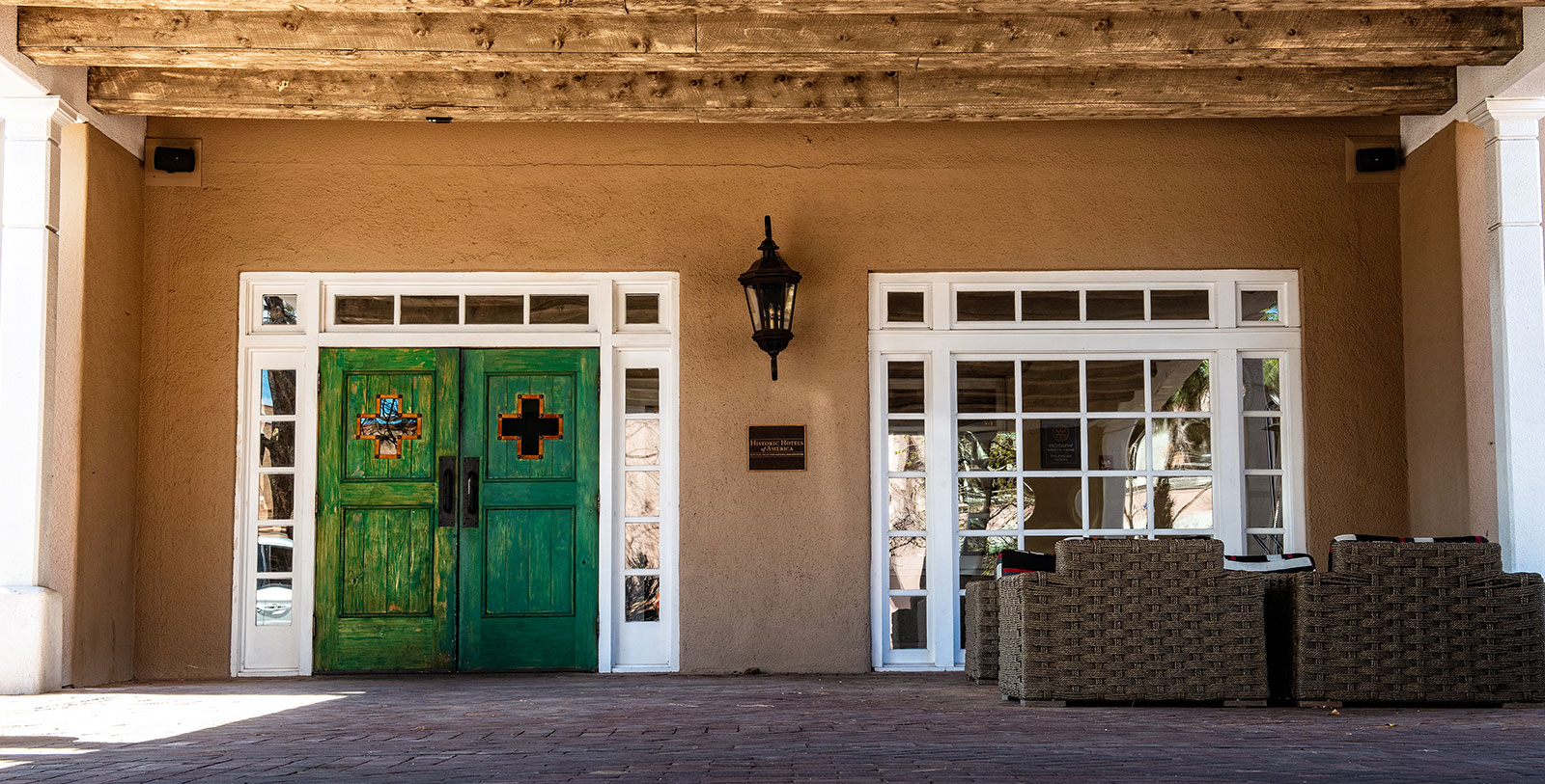 a green doors and a lamp on a brick wall
