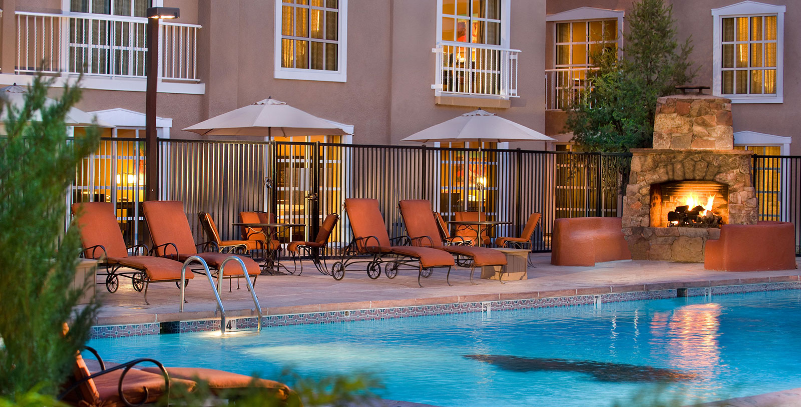 a pool with chairs and umbrellas by a building