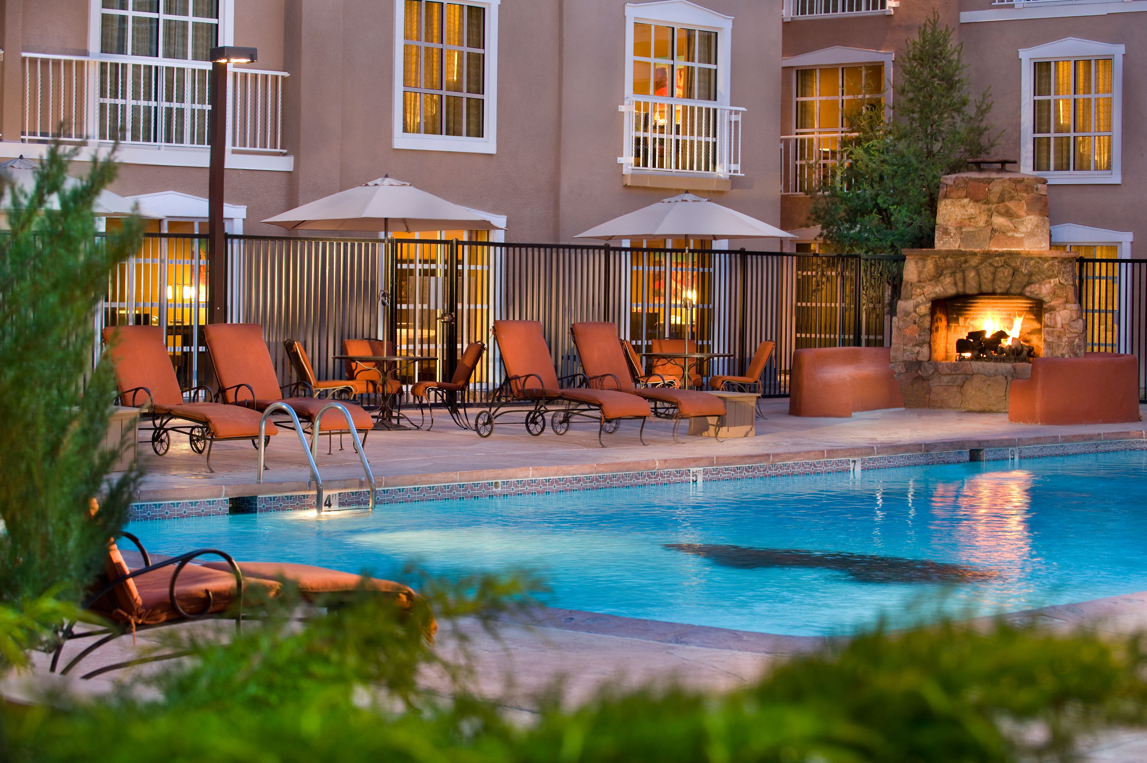 a pool with chairs and umbrellas in front of a building