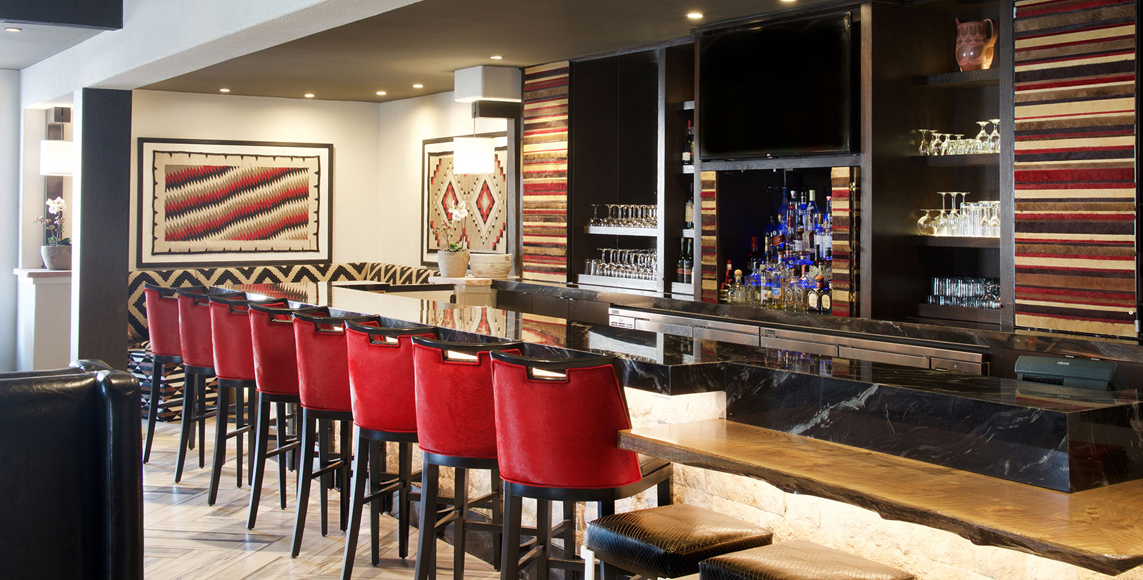 a bar with red chairs and a bar counter