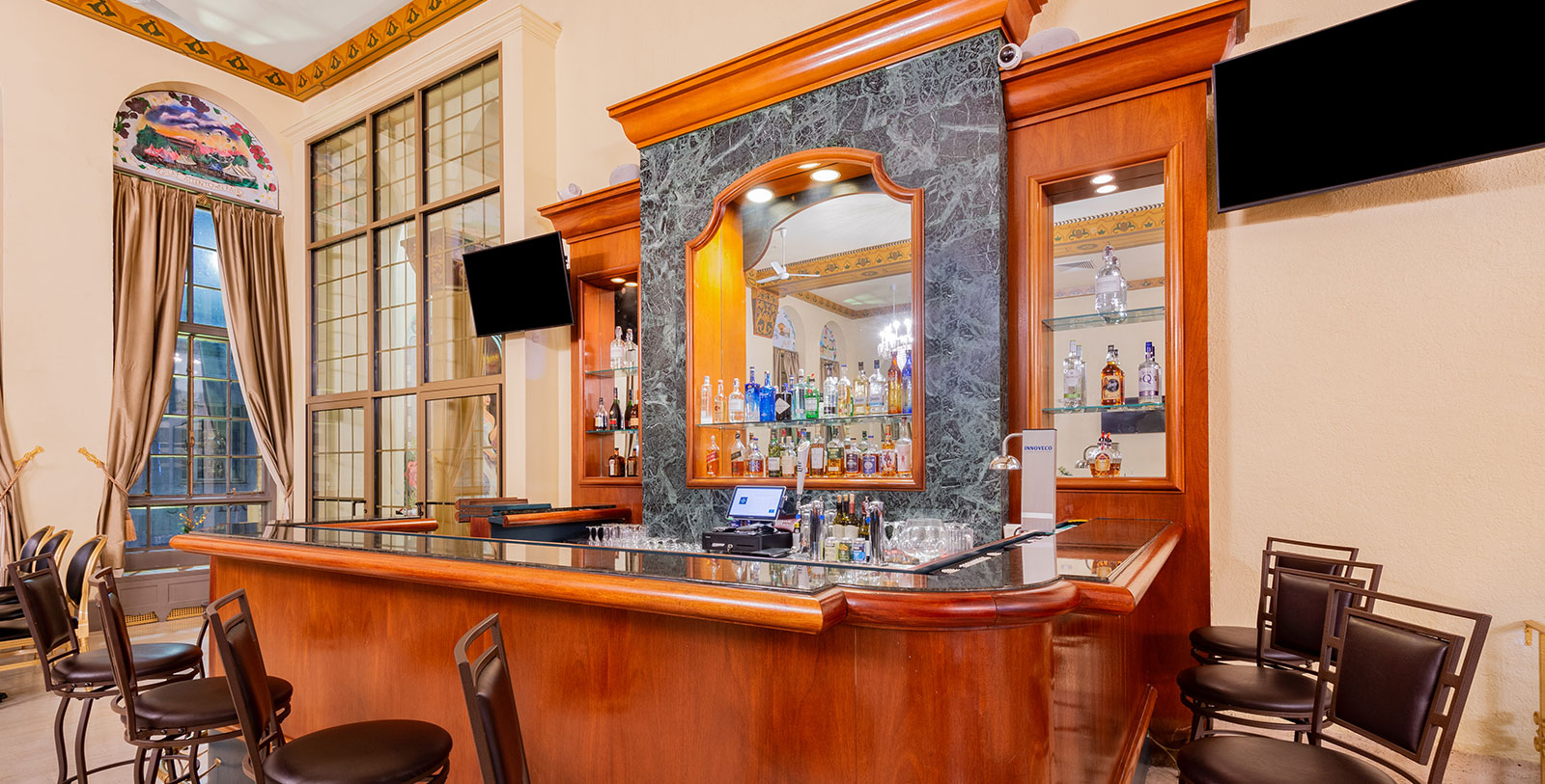 a bar with a mirror and bottles on the wall