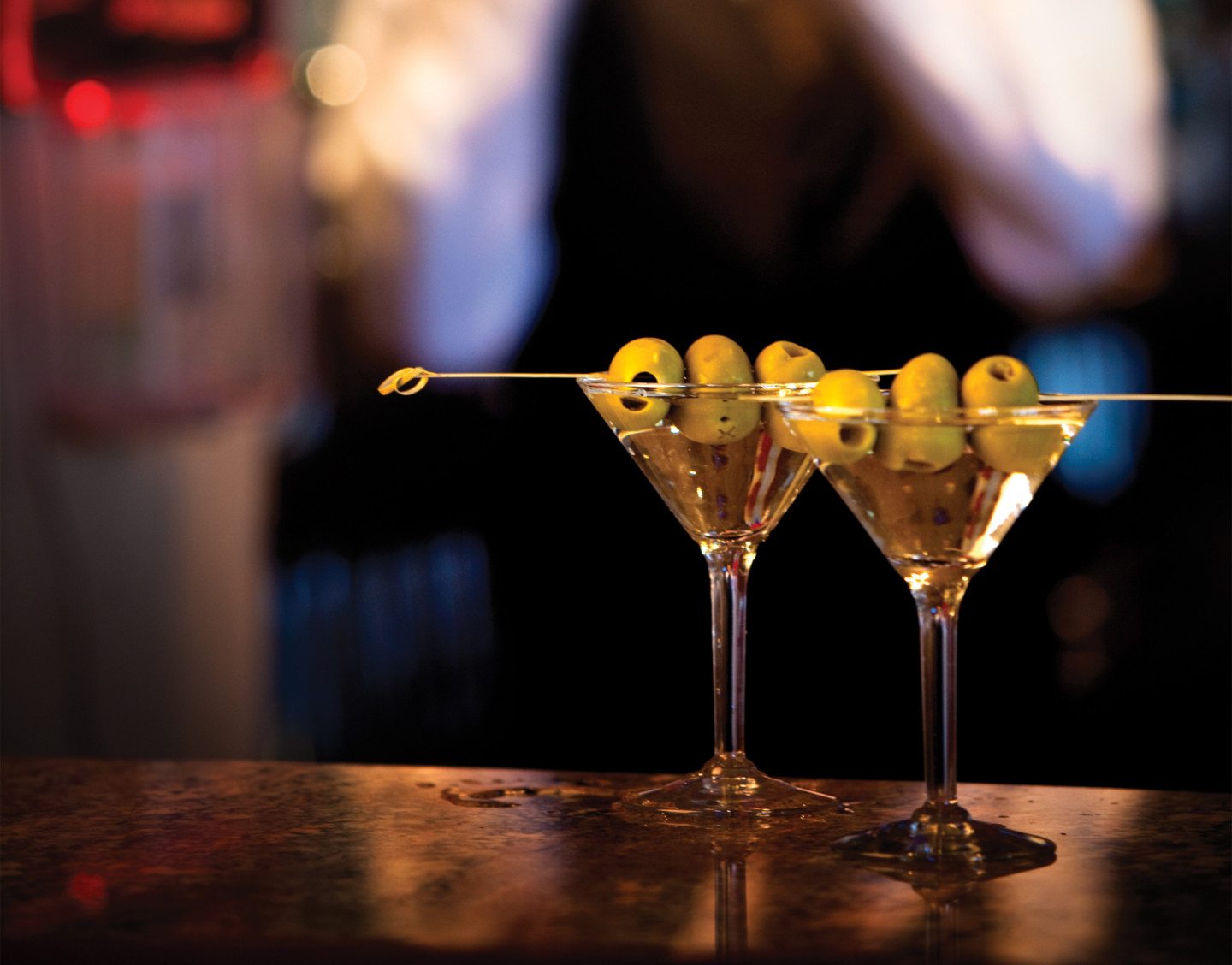 a pair of martini glasses with olives on a stick
