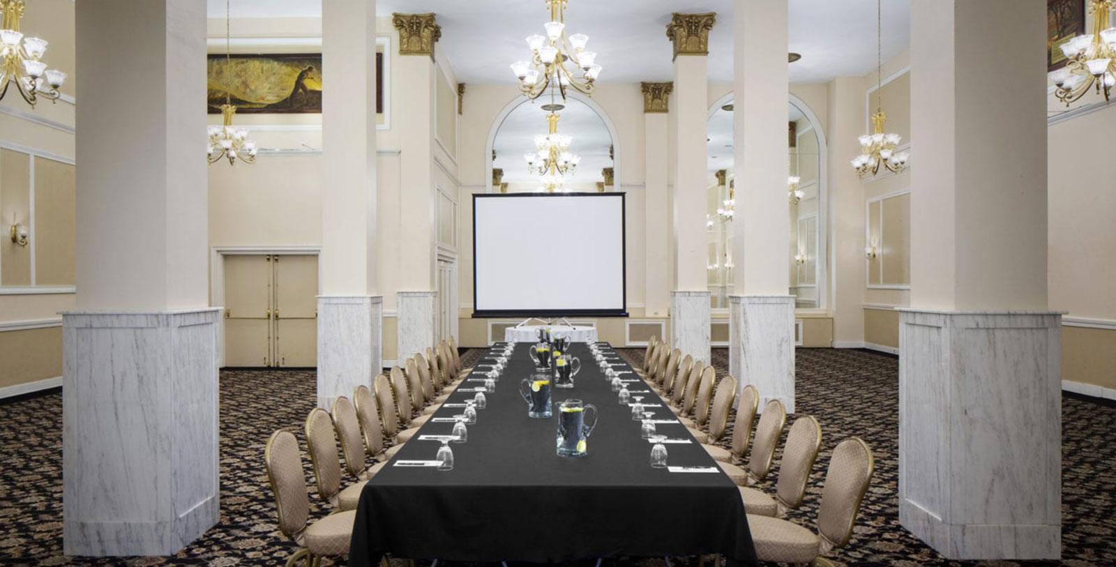a long table with glasses and a black tablecloth in a room with chairs