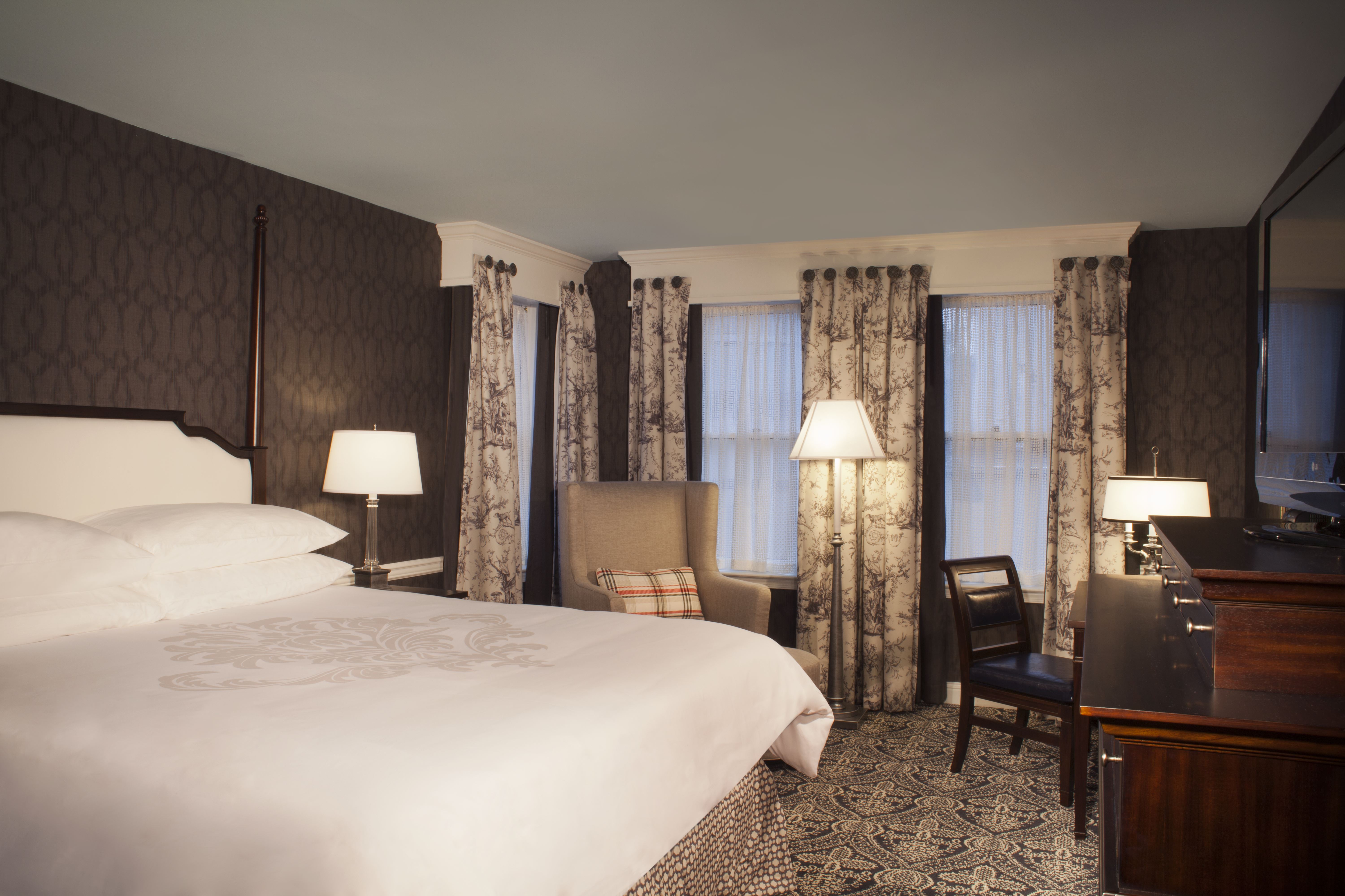 a room with a bed and chairs
