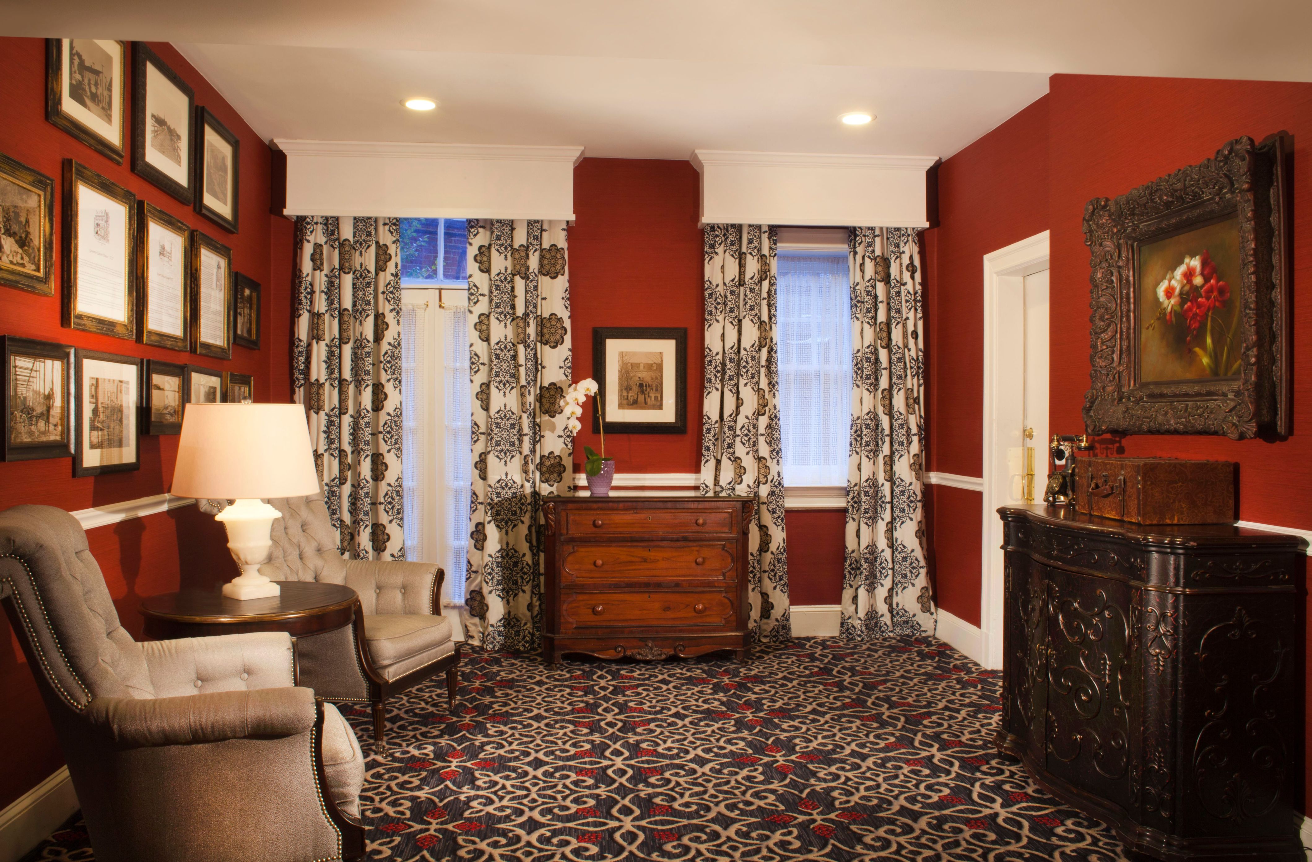 a room with red walls and a dresser and chairs