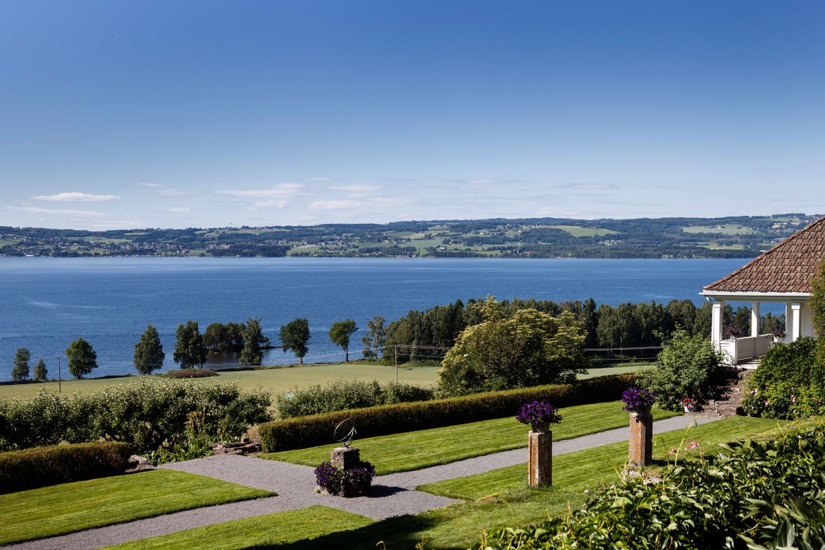 a landscape with a body of water and a path with flowers