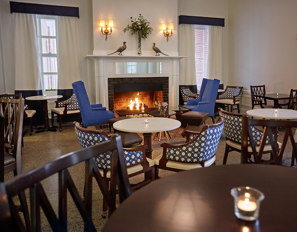 a room with a fireplace and tables and chairs