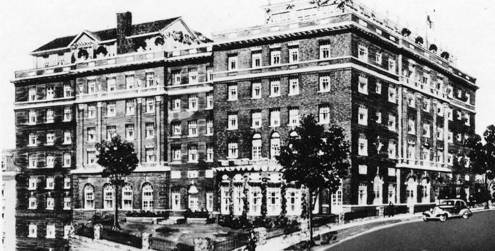a large brick building with a fence and trees