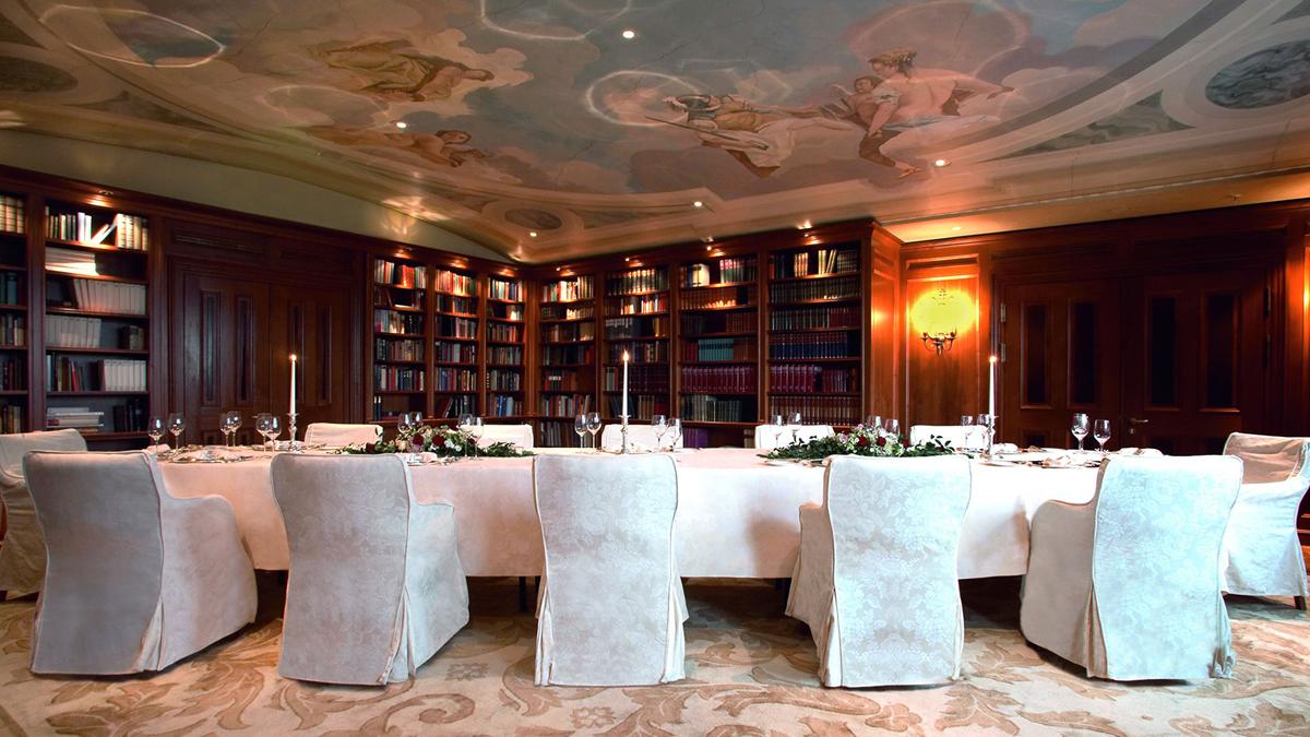 a long table with white chairs and candles