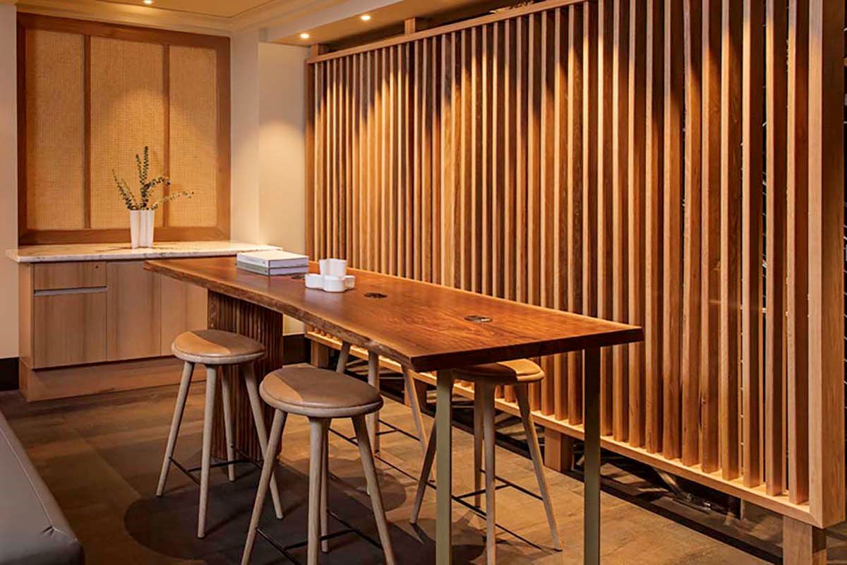 a table with stools and a plant in front of a wood wall