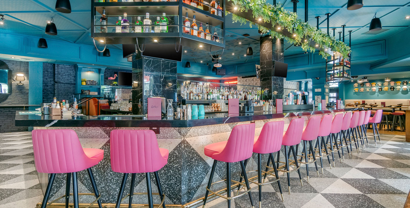 a bar with pink chairs and bottles