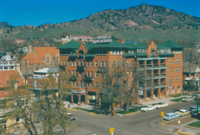 a building with a green roof and a parking lot with cars parked in front of it
