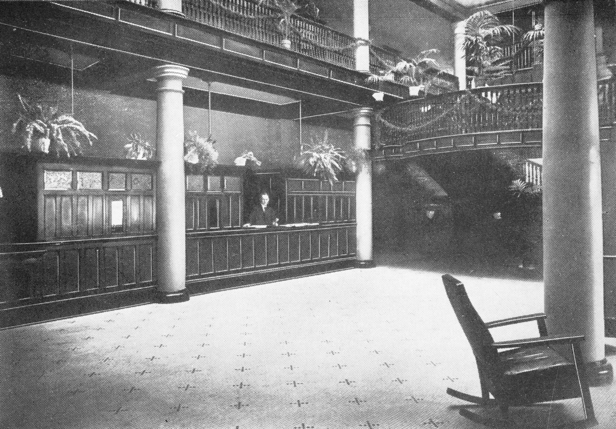 a black and white photo of a room with a desk and chairs