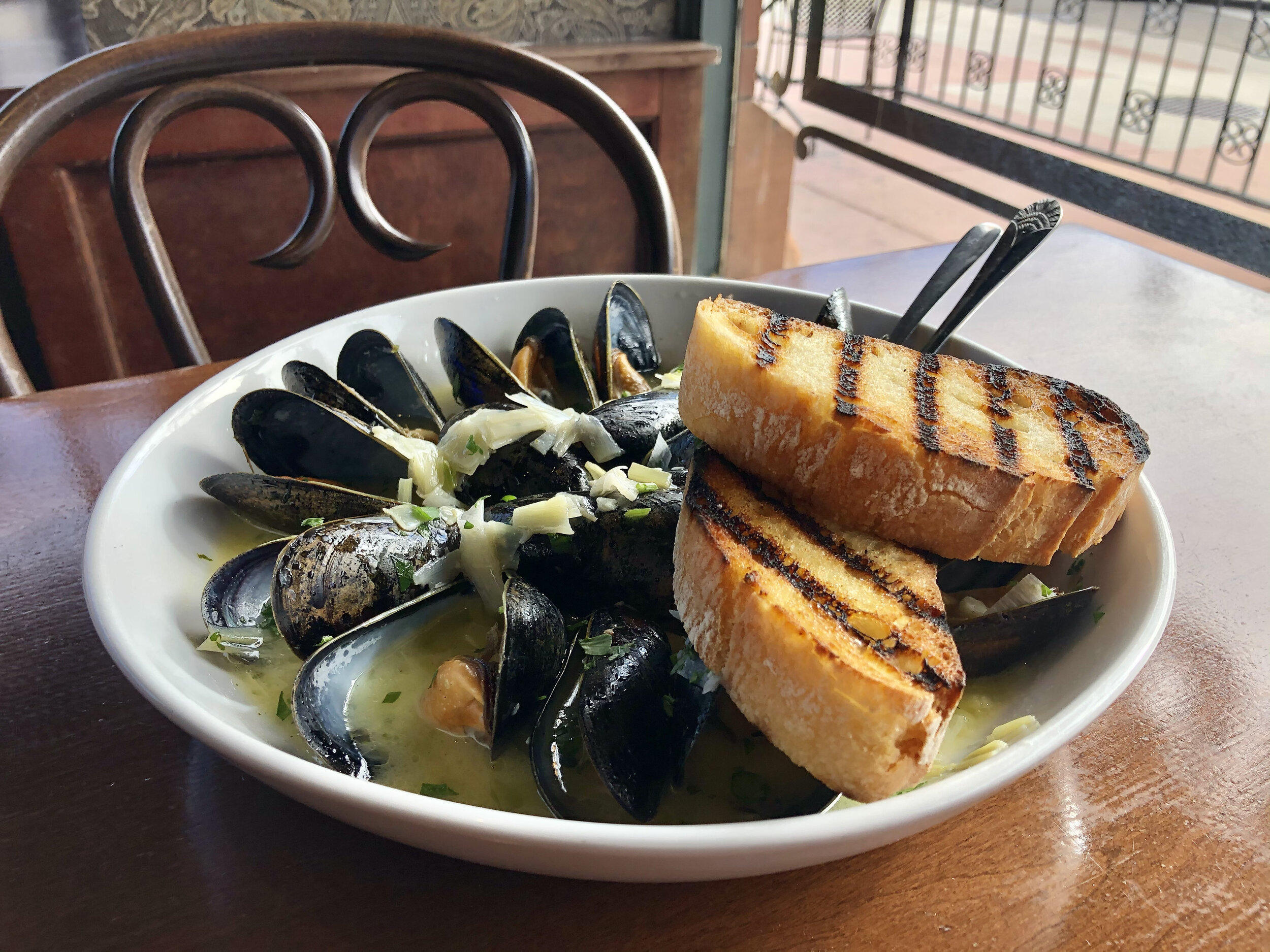 a bowl of soup with bread and mussels