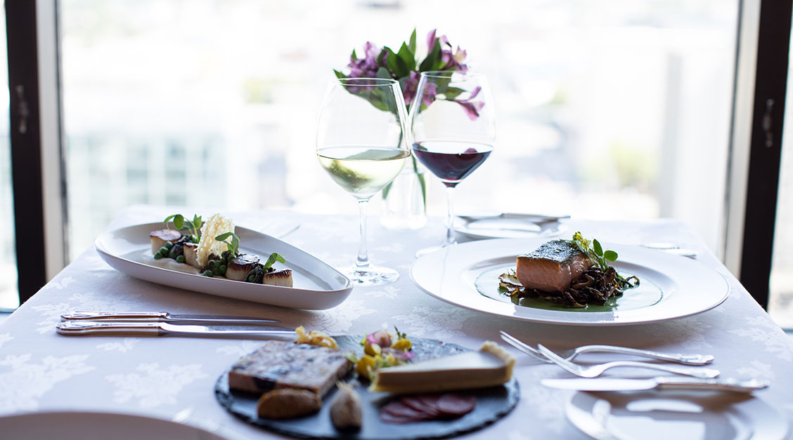 a table with plates of food and wine glasses