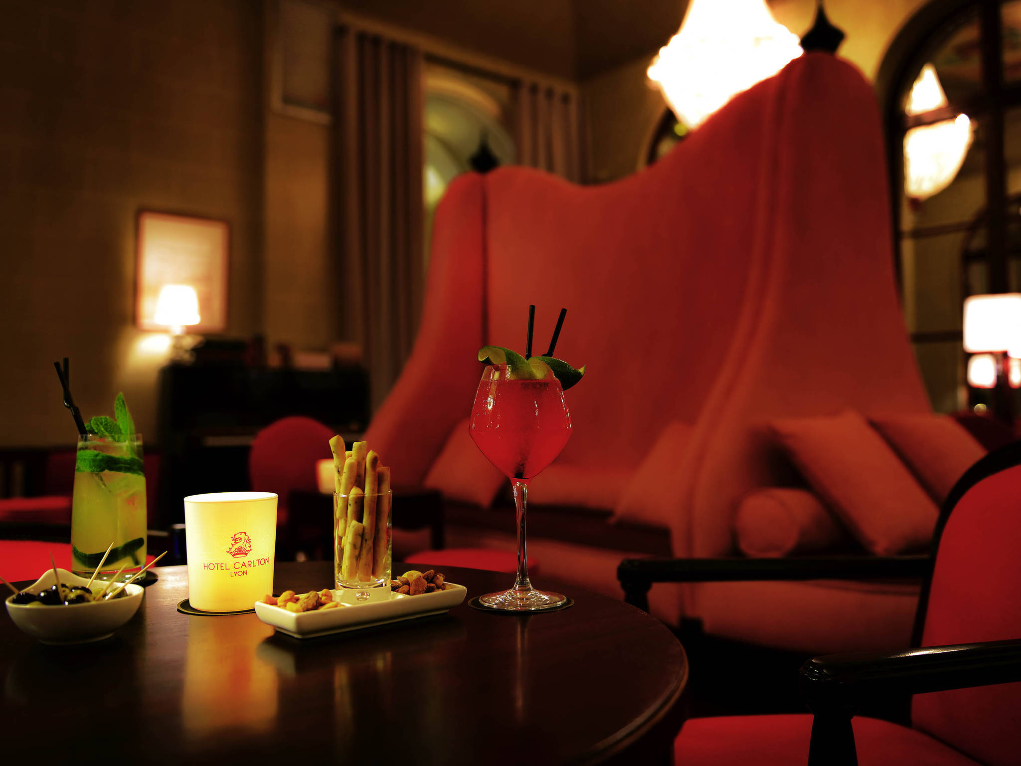 a glass of red liquid on a table with a red chair in the background