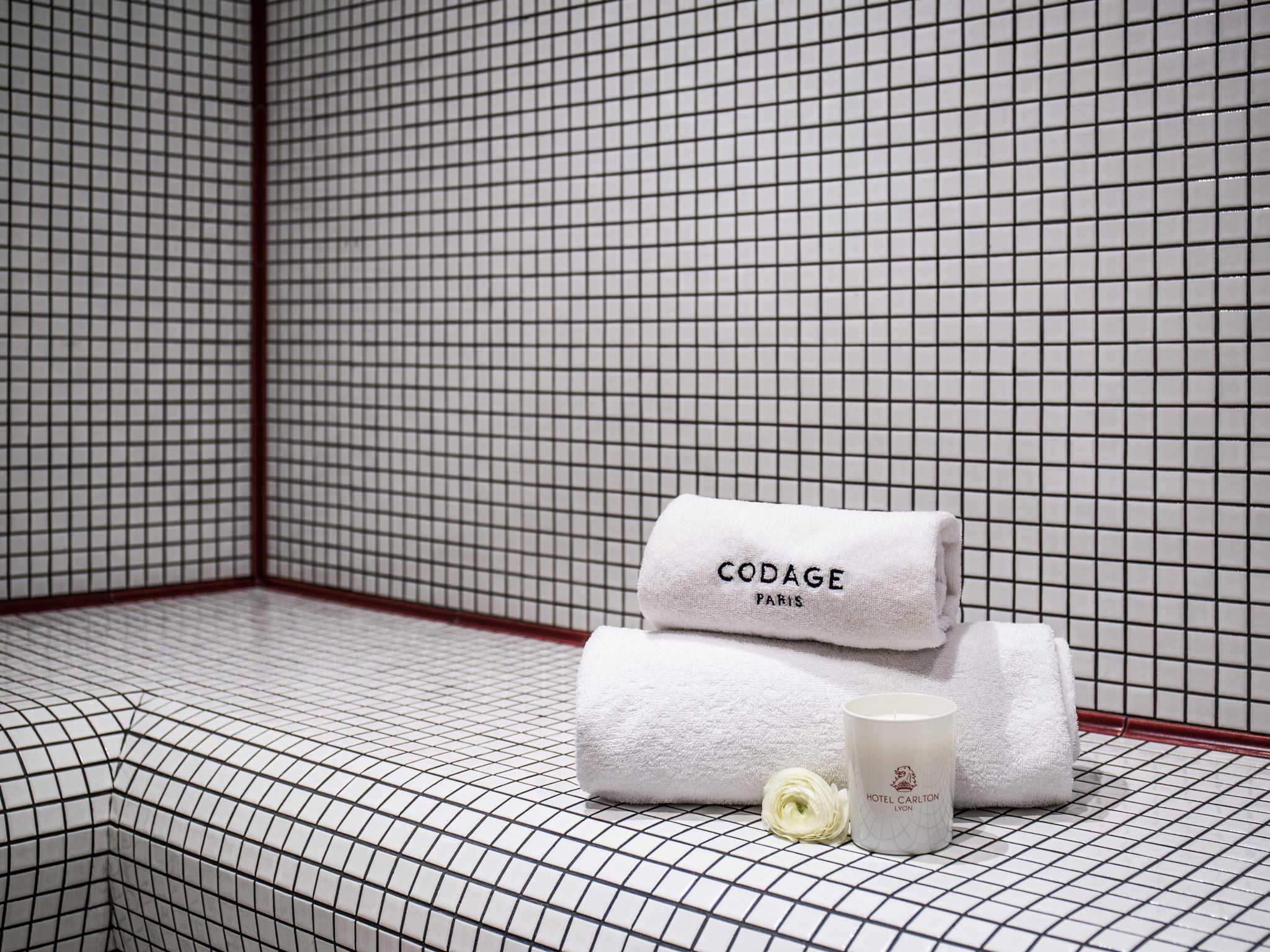 a white towels and a candle on a tile surface