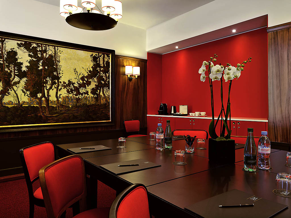 a room with red chairs and a table with a painting on the wall