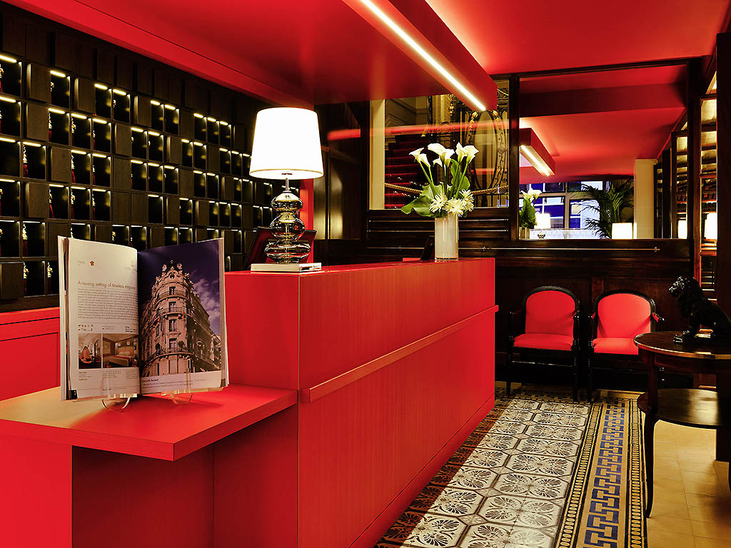 a red reception desk with a lamp and a vase of flowers