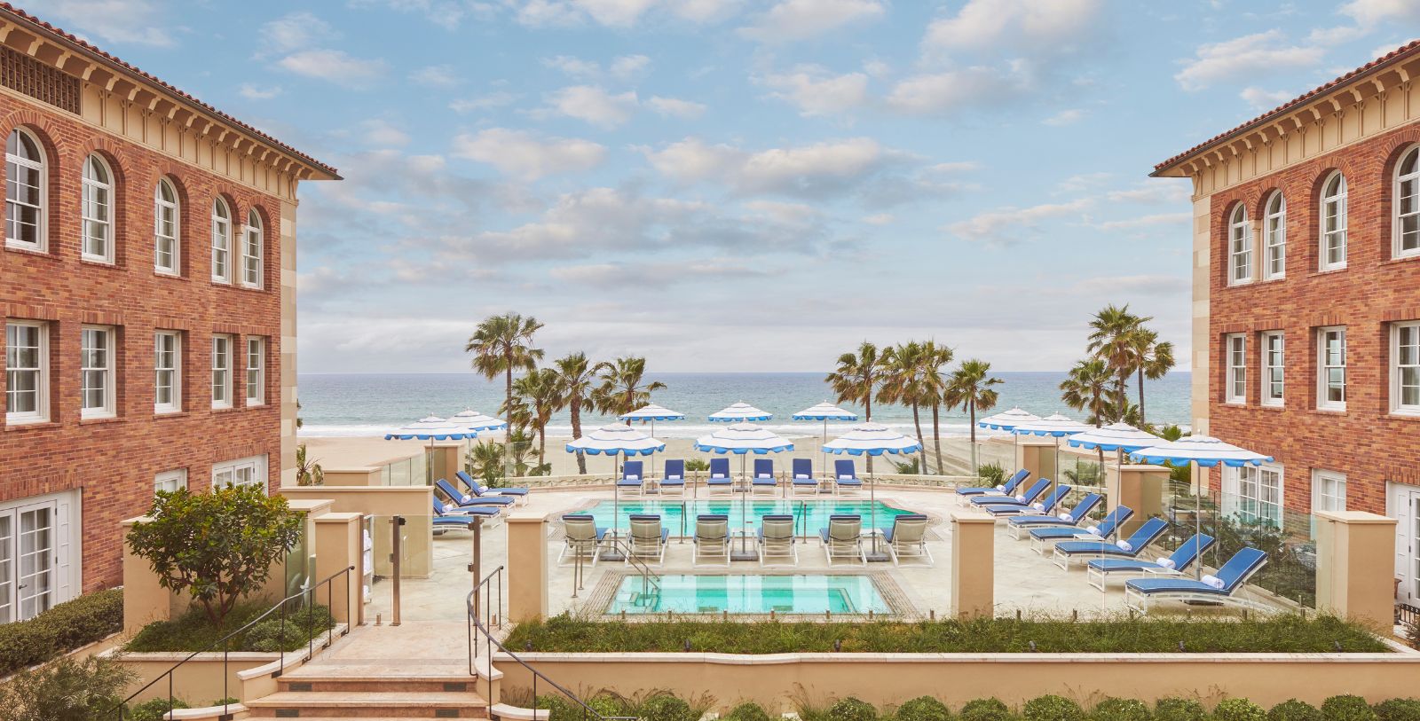 a pool with umbrellas and chairs on the beach