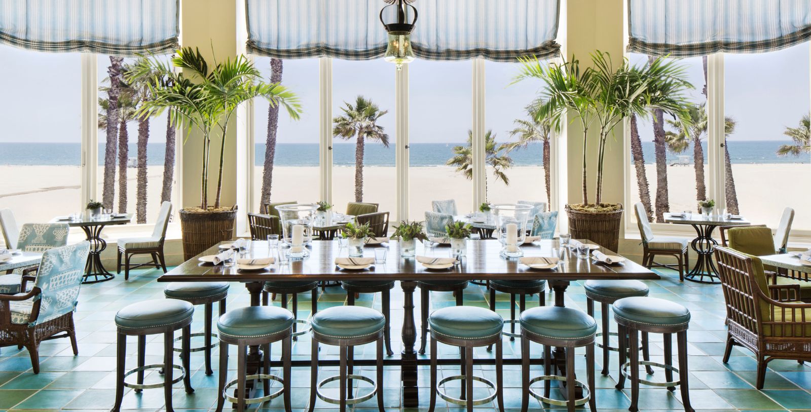 a table with chairs and palm trees in front of a large window