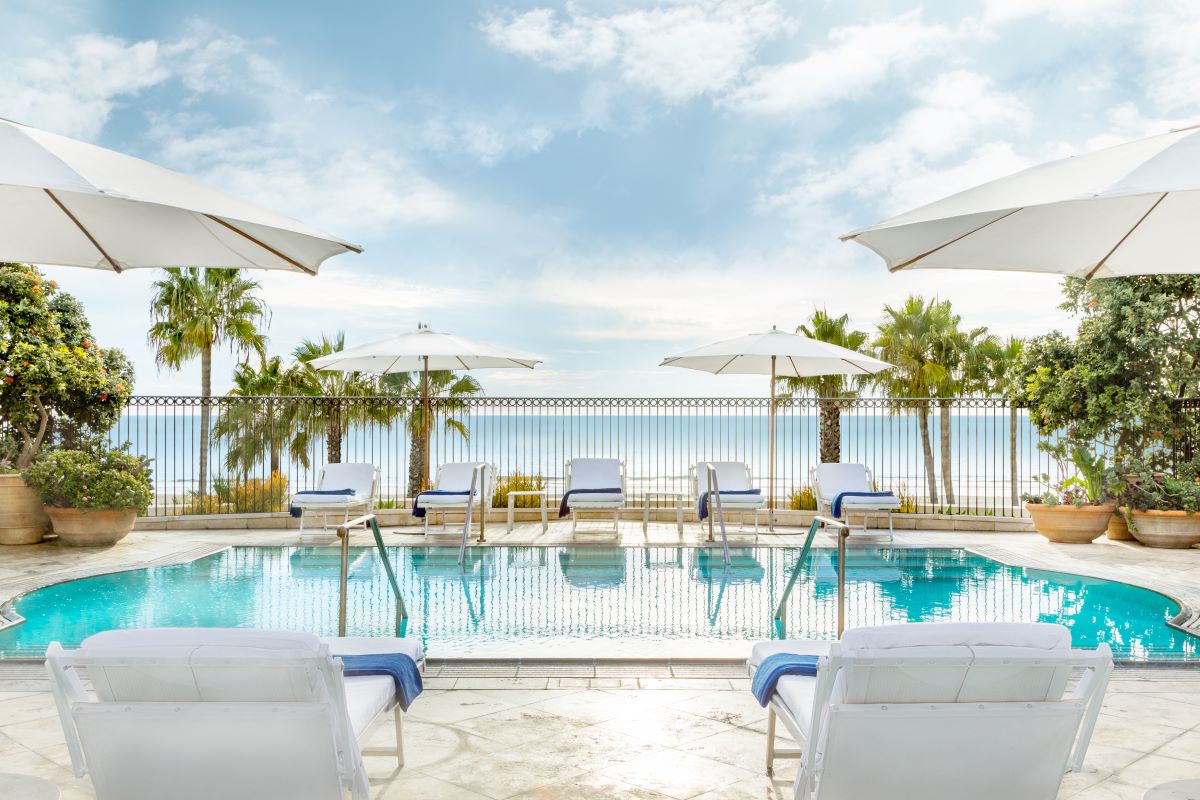 a pool with chairs and umbrellas by a fence