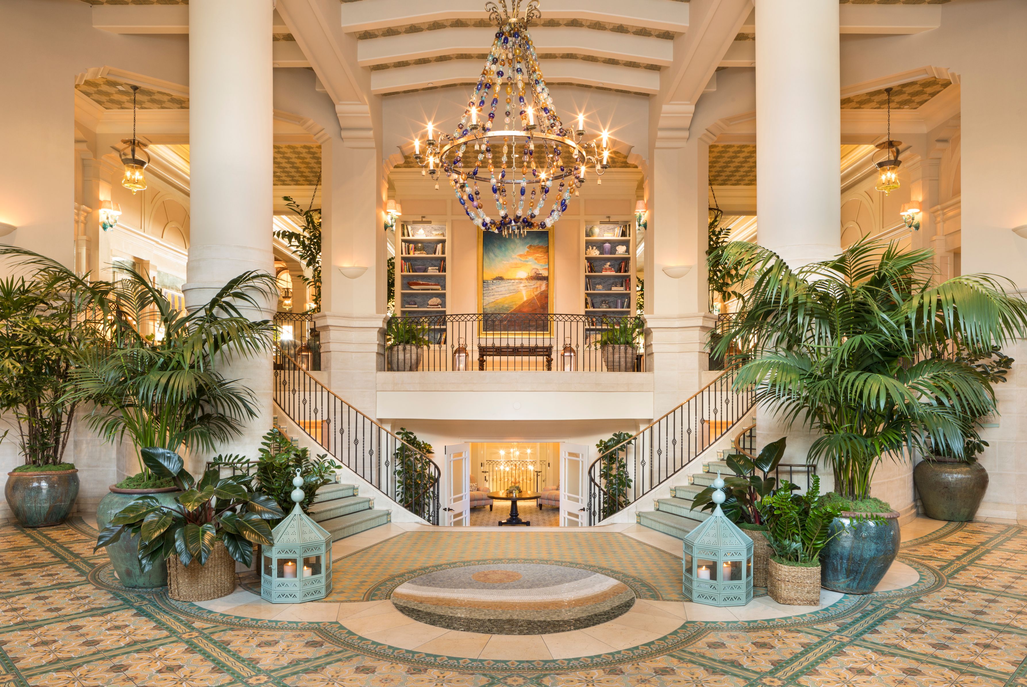 a large chandelier in a large room with a staircase and plants
