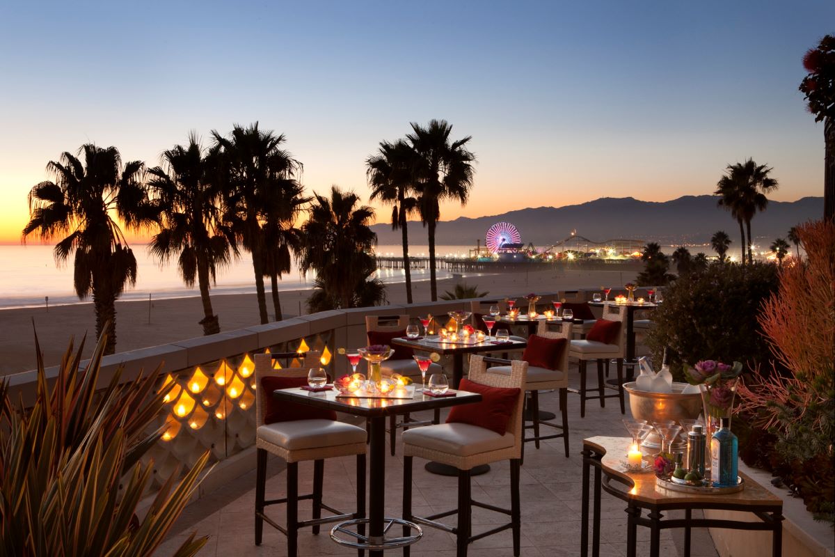 a table set up on a patio with palm trees and a ferris wheel in the background