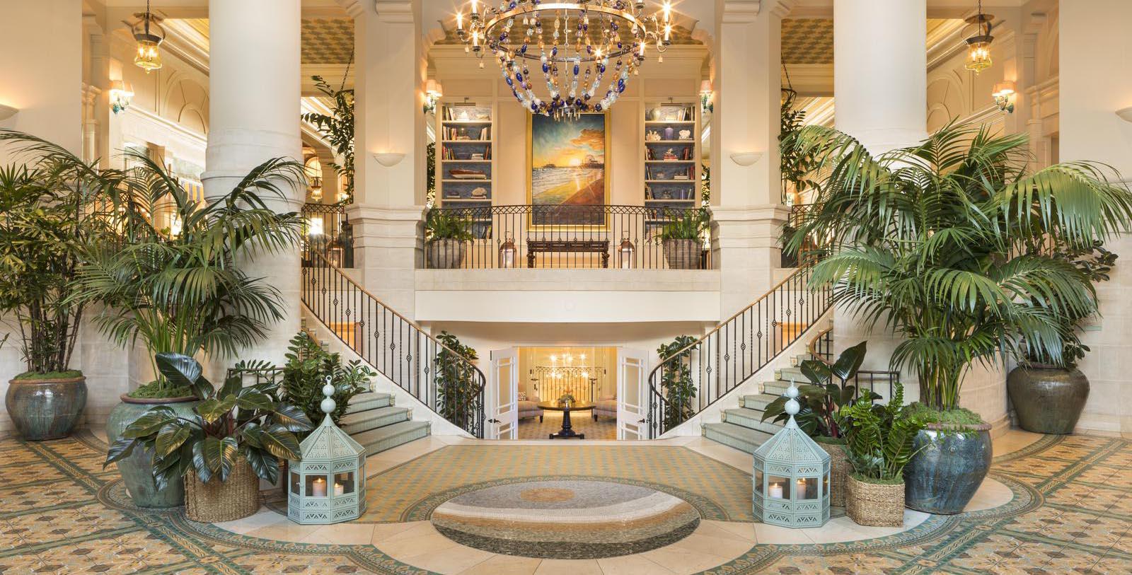 a large staircase with a chandelier and plants