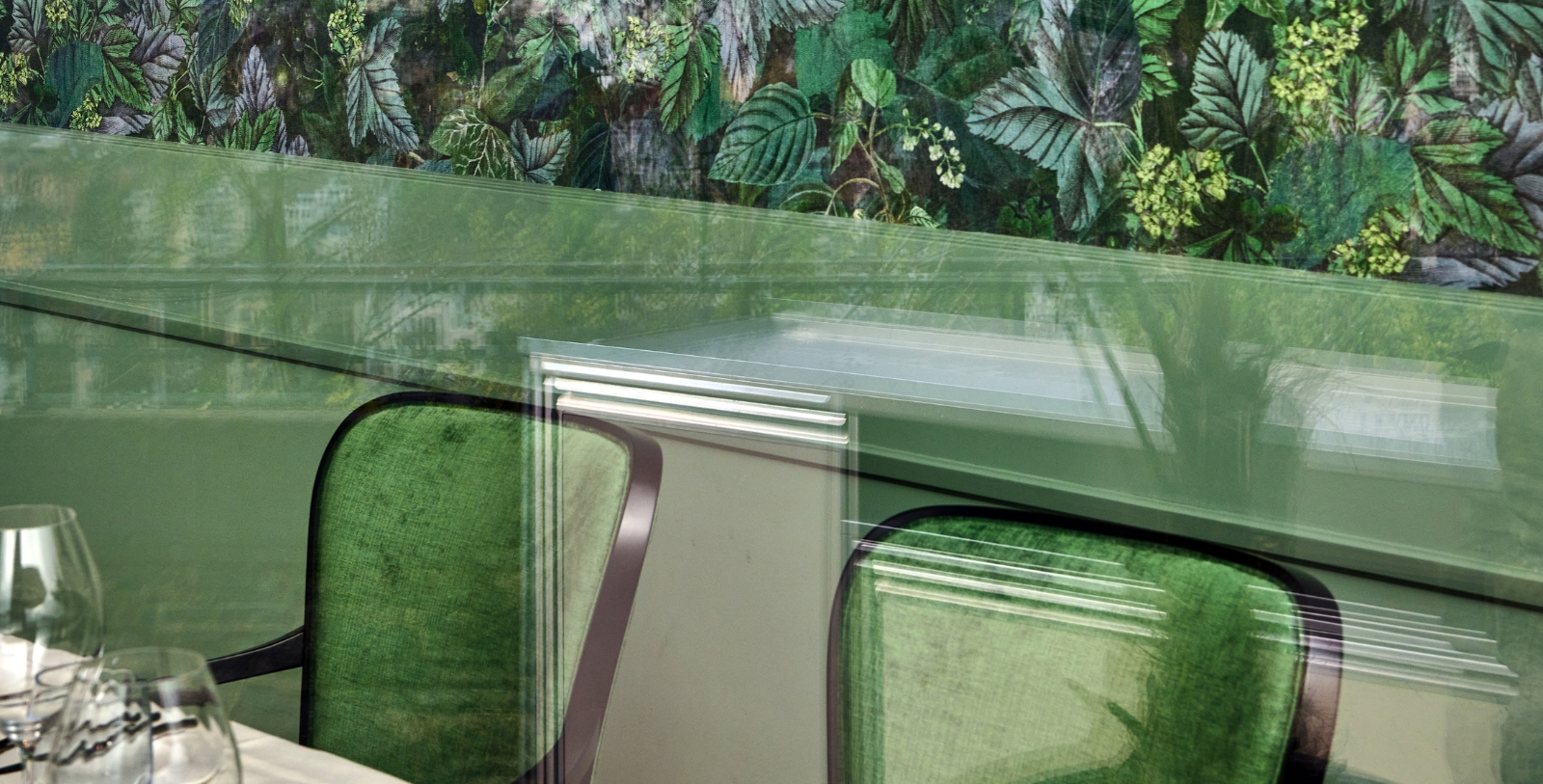a green chairs with a wall of leaves