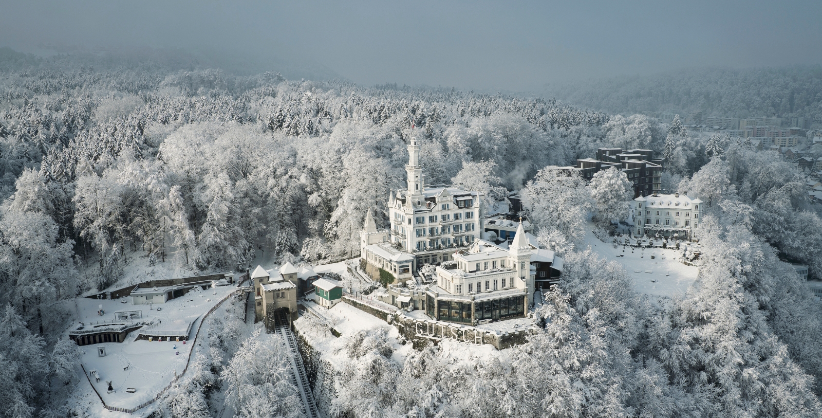 a building with a tower on a hill covered in snow