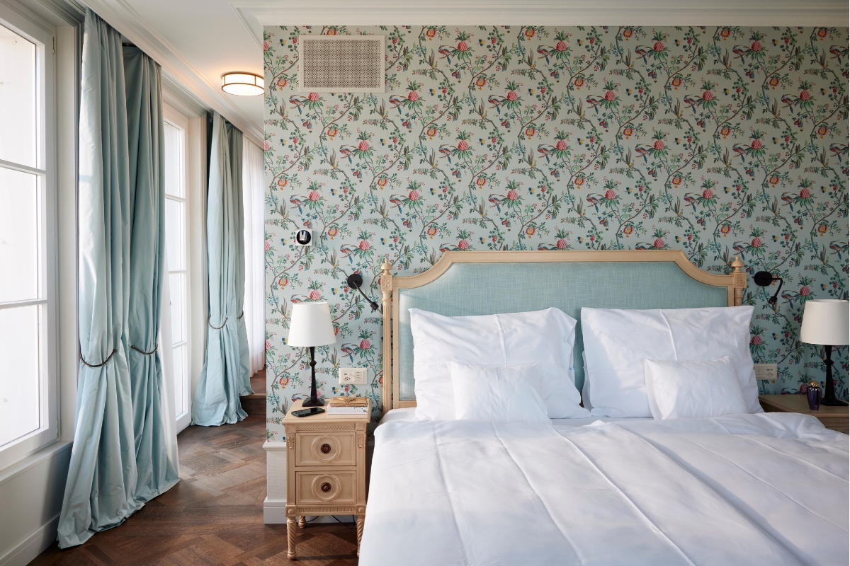a bed with a lamp on a nightstand in a room with floral wallpaper