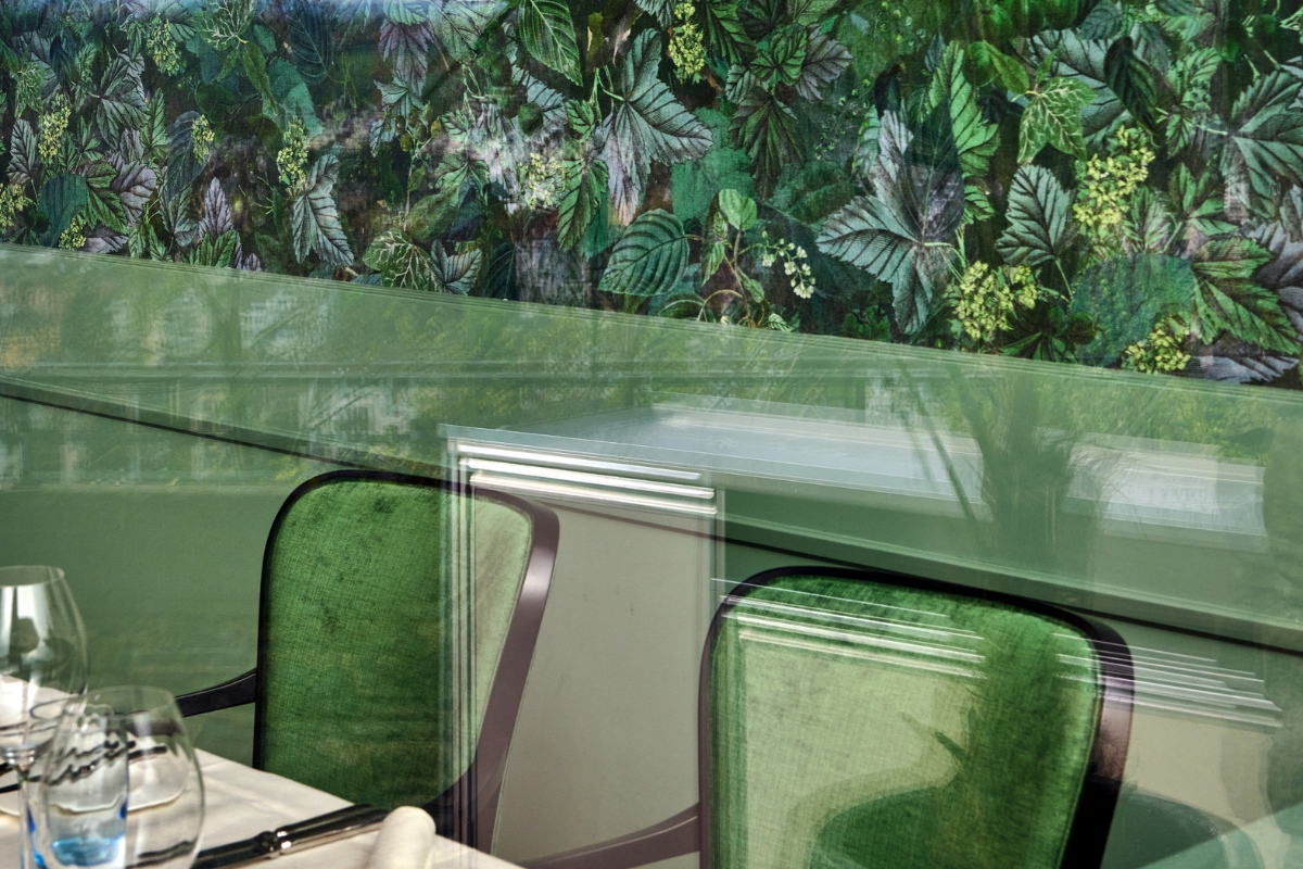 a green chairs with a wall of leaves