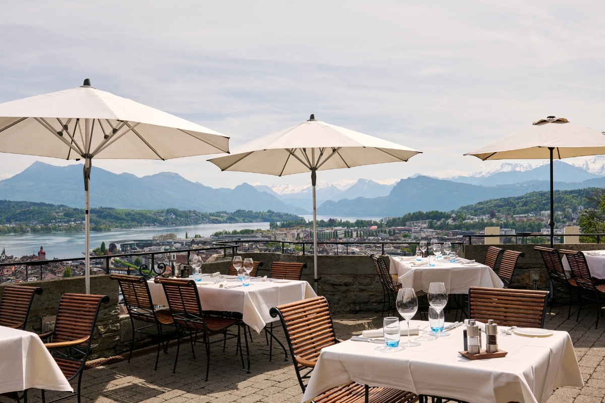 a table and chairs with umbrellas and a city in the background