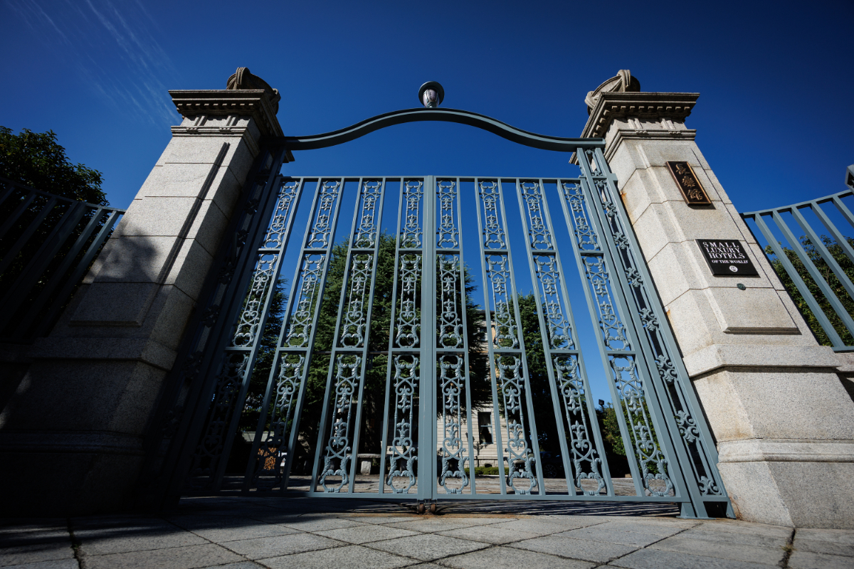 a gate with a stone wall and a building in the background