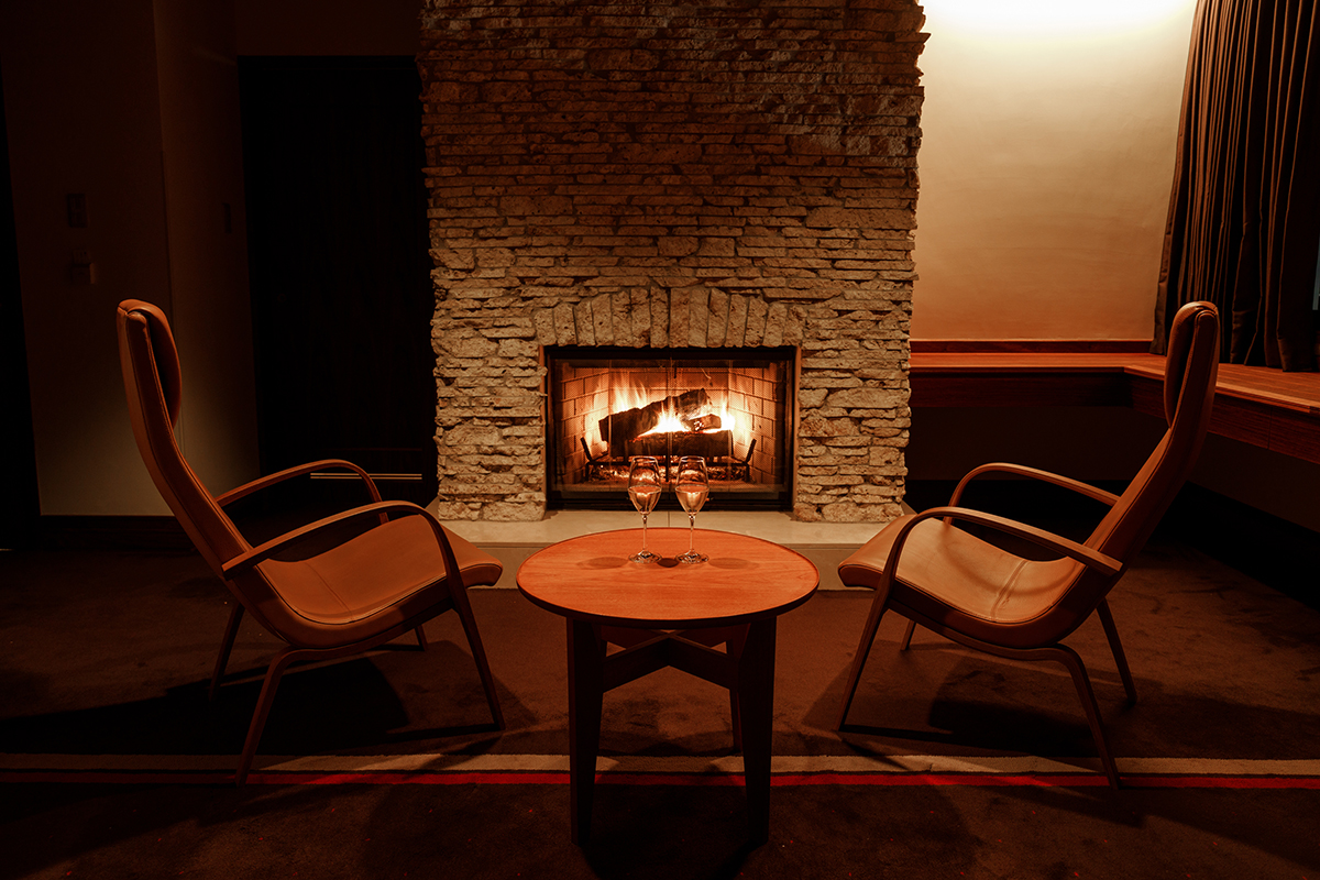 a table with wine glasses in front of a fireplace