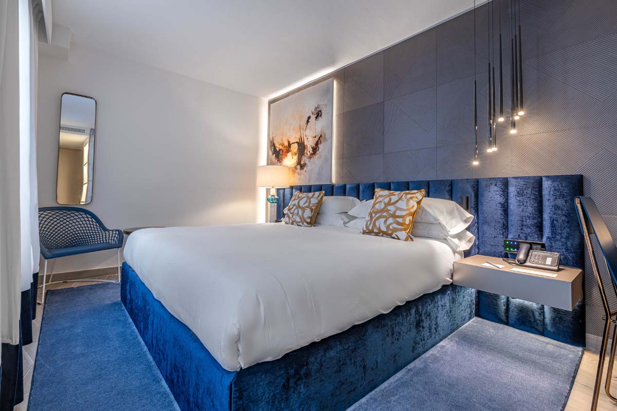 a bed with a blue headboard and a lamp