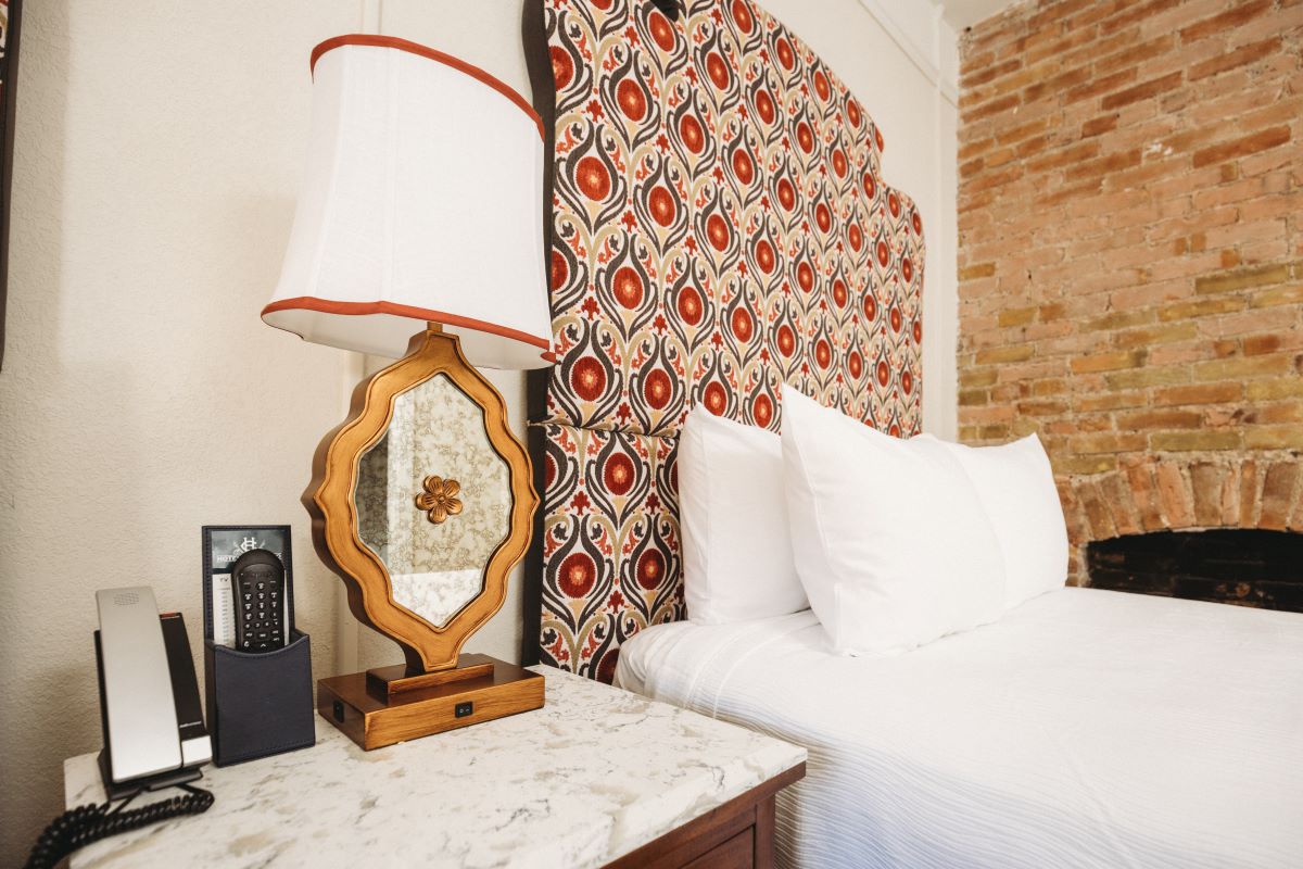 a bed with a lamp and a telephone on a table