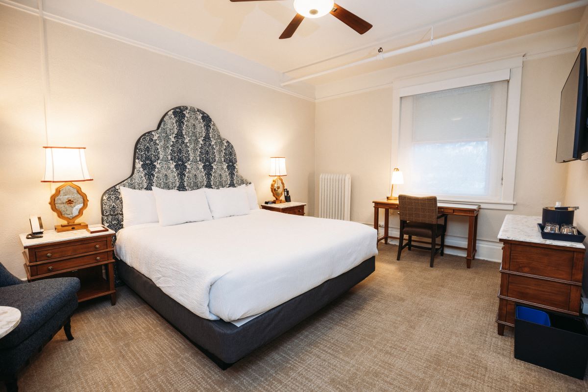 a bed with a fan and a desk in a room