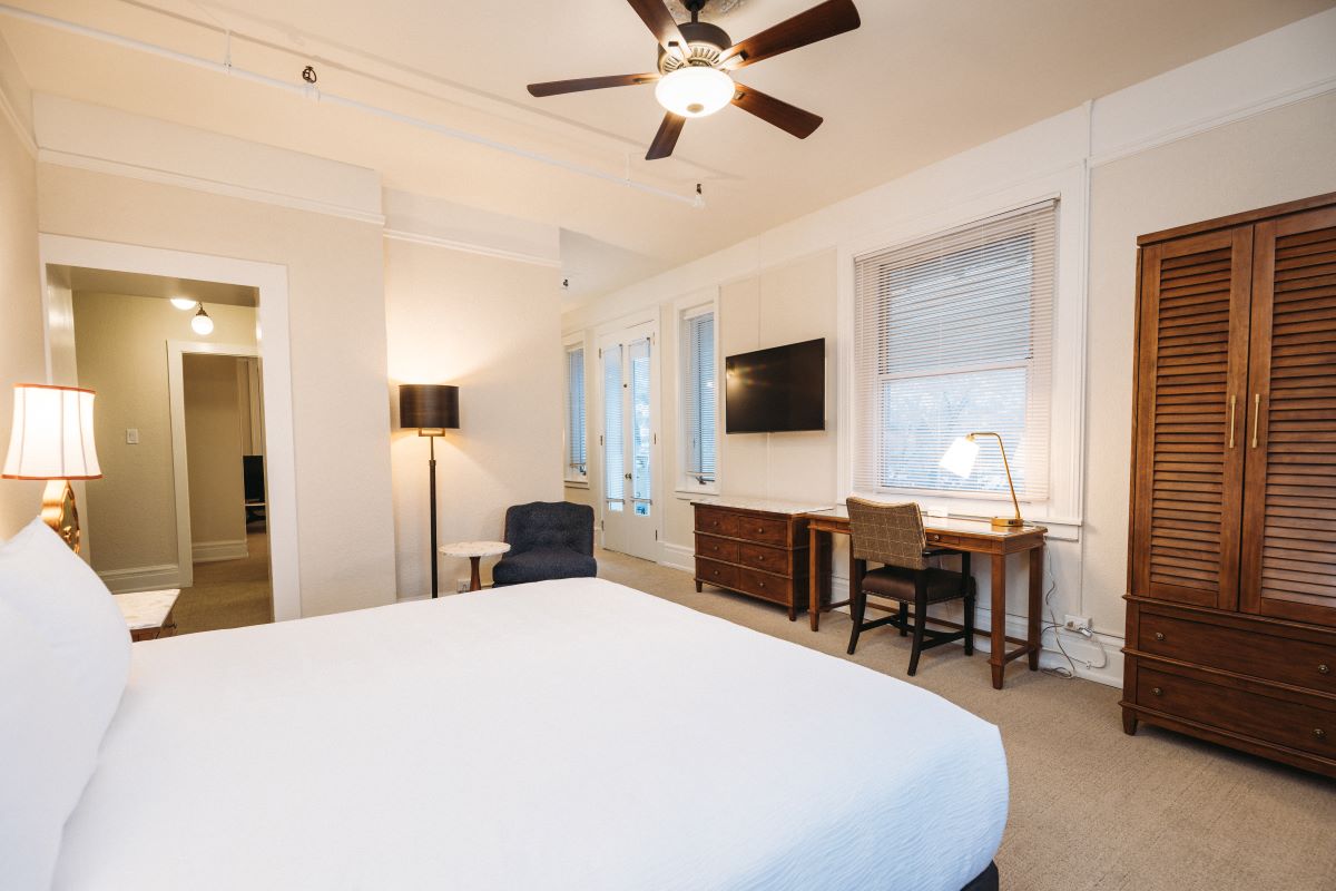 a room with a bed and a desk and a fan