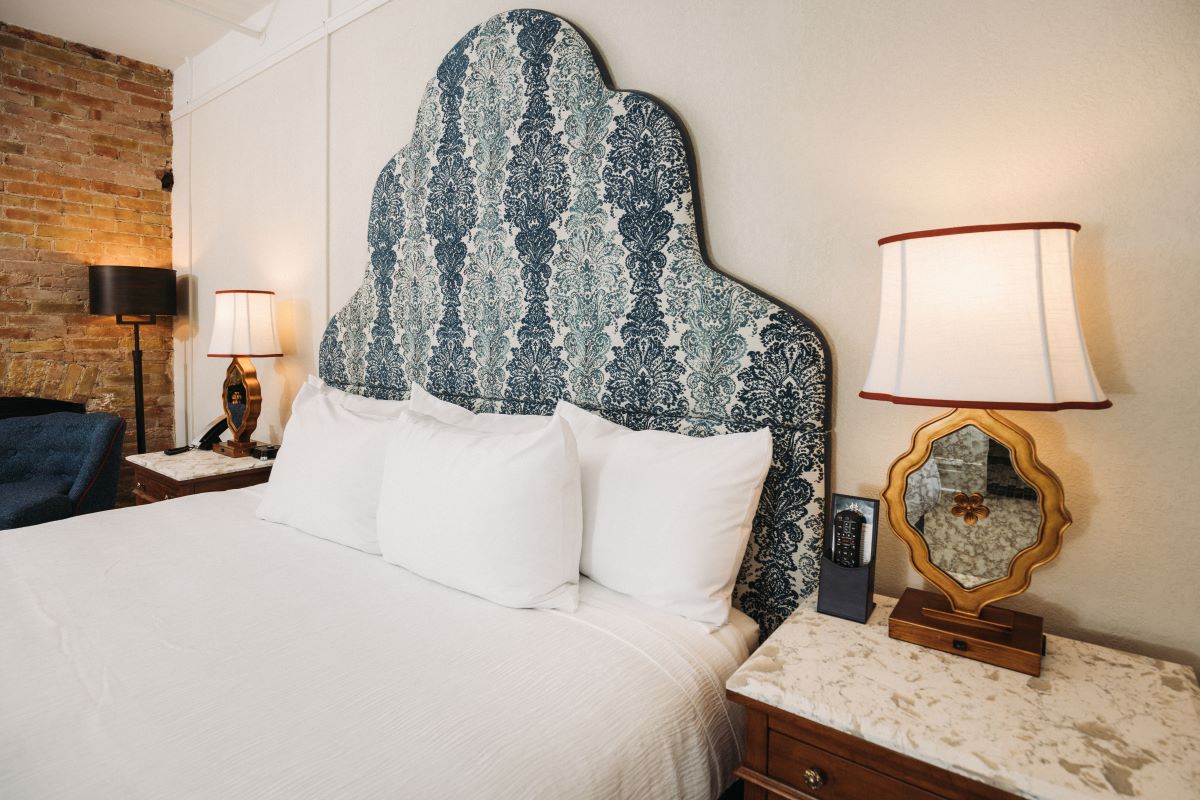 a bed with a patterned headboard and lamps